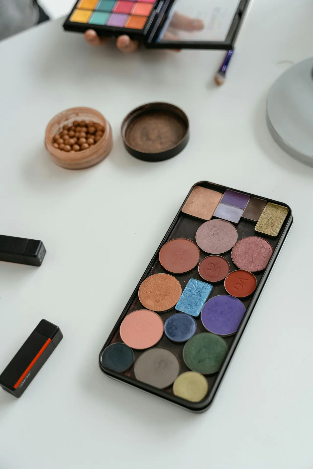 Minimalistyczny zestaw podstawowych kosmetyków do makijażu ułożony na białym tle